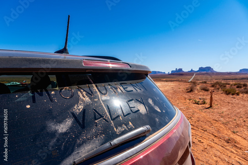 A vehicle featuring the phrase monument valley displayed on its rear window, with Monument Valley in background, USA