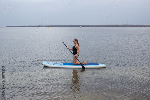 Woman on stand up paddle board. Stand up paddle boarding on a quiet lake
