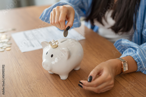 close up on adult woman hands put coins at piggy bank