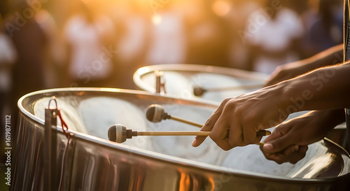 Close-up of a musician's hands playing steel pan drums at a vibrant outdoor festival during a golden sunset.