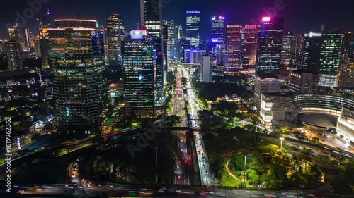 Cinematic timelapse aerial of Jakarta city skyline at night with illuminated skyscrapers, glowing cityscape, and busy traffic. Modern urban life in Southeast Asia.
