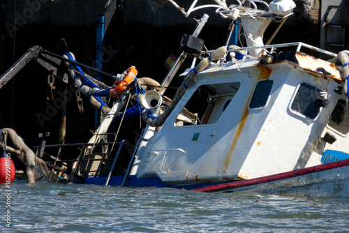 Sunken fishing boat partially submerged in harbor, maritime accident scene