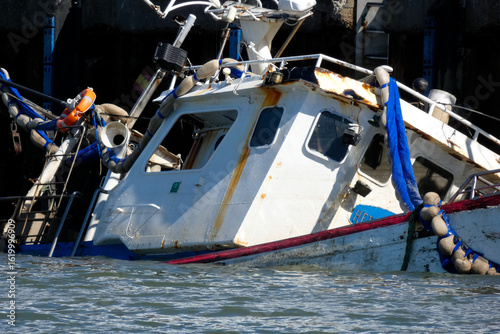Sunken fishing boat partially submerged in harbor, maritime accident scene
