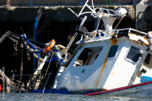 Sunken fishing boat partially submerged in harbor, maritime accident scene