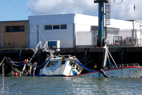 Sunken fishing boat partially submerged in harbor, maritime accident scene