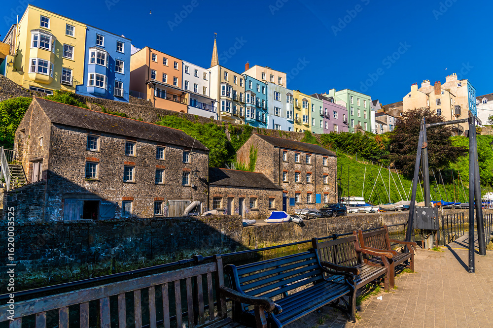 Fototapeta premium A view towards coloured buildings above the harbour in the early morning in Tenby, South Wales in summertime