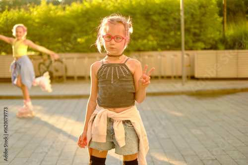 Quadro em tela Young girl with pink glasses skateboarding outdoors at sunset, wearing casual bl