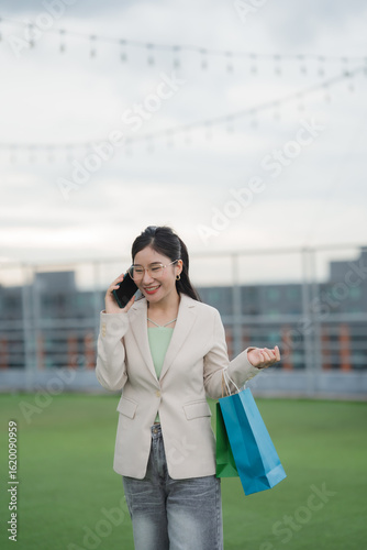 Картината върху платно Joyful Shopper on Call: A content woman, phone in hand, strides with shopping bags, radiating cheerfulness against a sky backdrop