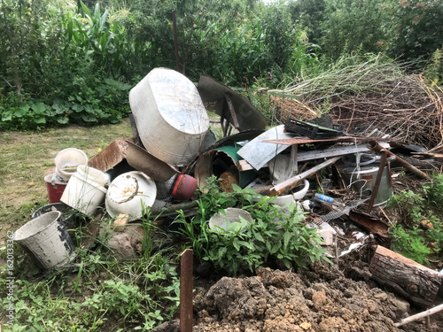Debris pile shows neglect in overgrown garden area