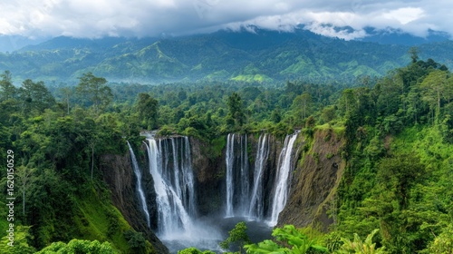 Lush waterfall cascading into a valley, surrounded by vibrant green jungle and misty mountains