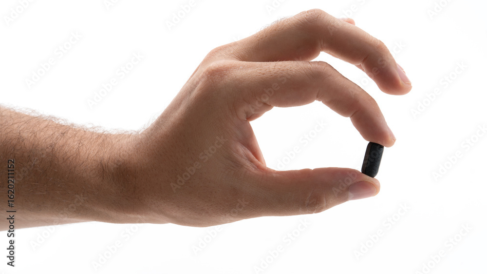 Fototapeta premium Hand holding a black capsule