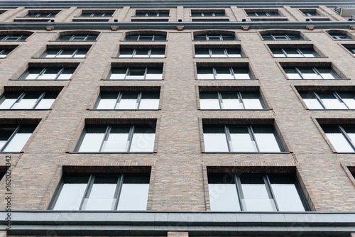 modern multi-storey apartment building, brown brick building with glass windows, urban background