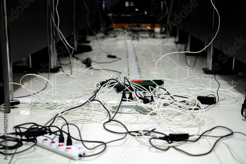 Messy network and power cables tangled on the floor in a meeting room, representing poor cable management, office hazards, or IT infrastructure setup challenges.