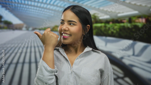 Woman raises thumb pointing along street where a young latin hispanic individual stands outdoors smiling amid urban scenery. Free Download Woman raises thumb pointing along street where a young latin hispanic individual stands outdoors smiling amid urban scenery. - GFXLoad