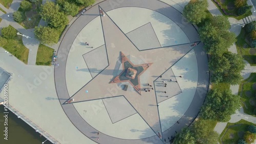 Aerial video of Astrakhan waterfront, star-shaped ornament with Peter the Great monument overlooking the Volga River under soft daylight.
