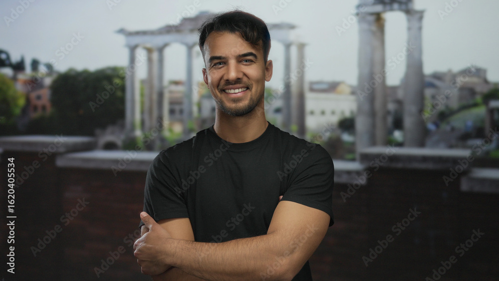 Fototapeta premium Young man smiling in front of ancient roman ruins in an outdoor city setting, showcasing historical architecture and urban lifestyle.