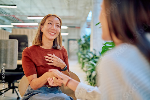 Cuadro en lienzo Two asian businesswomen shaking hands during a meeting in a modern office, showi