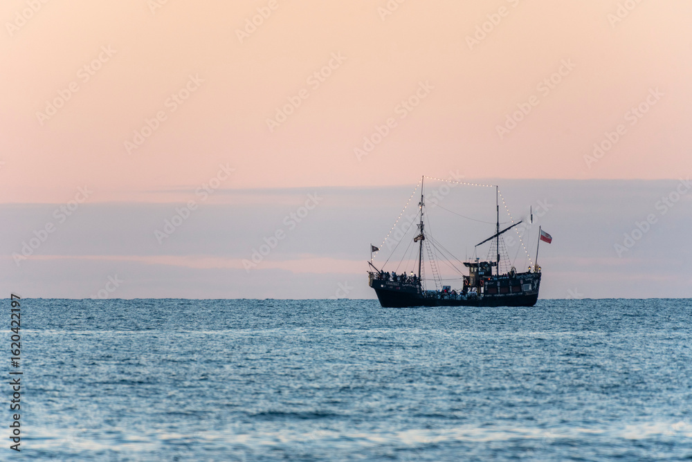 A tourist ship styled like an old galleon sails through the calm waters of the Baltic Sea along the Polish coast, carrying passengers enjoying a scenic maritime journey. A tourist ship styled like an old galleon sails through the calm waters of the Baltic Sea along the Polish coast, carrying passengers enjoying a scenic maritime journey.