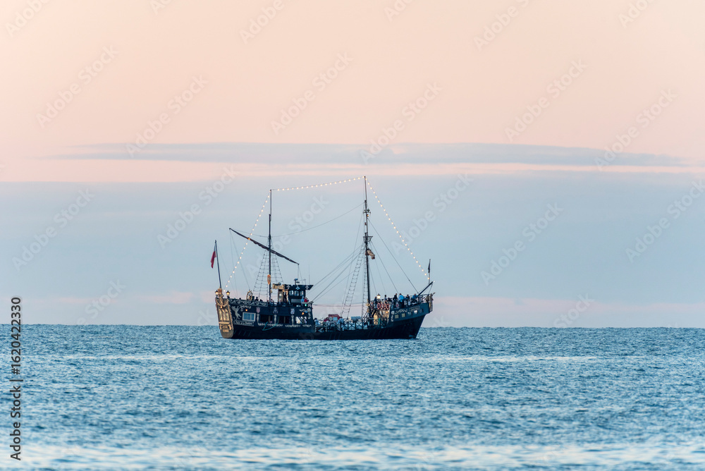 A tourist ship styled like an old galleon sails through the calm waters of the Baltic Sea along the Polish coast, carrying passengers enjoying a scenic maritime journey. A tourist ship styled like an old galleon sails through the calm waters of the Baltic Sea along the Polish coast, carrying passengers enjoying a scenic maritime journey.