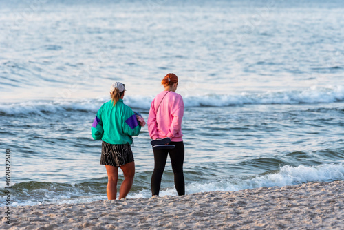 Fototapeta Naklejka Na Ścianę i Meble -  A couple walks along the sandy shore of the Baltic Sea, enjoying a peaceful seaside moment together.