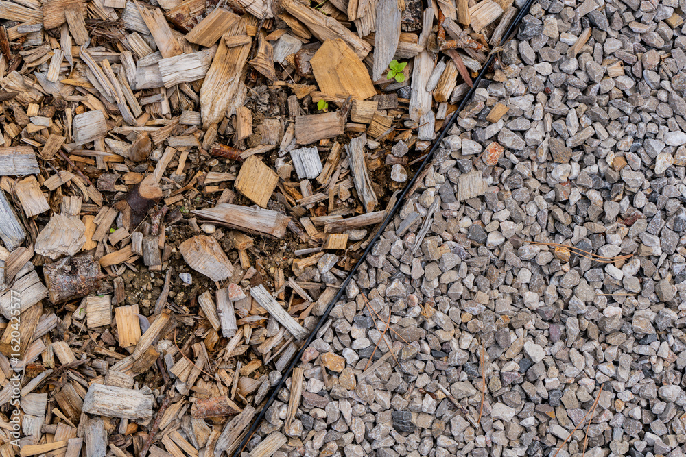 Zoom sur une zone de jardin délimitée avec des graviers d’un côté et des écorces décoratives de l’autre, mettant en valeur l’aménagement paysager et les contrastes de textures. Zoom sur une zone de jardin délimitée avec des graviers d’un côté et des écorces décoratives de l’autre, mettant en valeur l’aménagement paysager et les contrastes de textures.