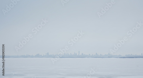 Silhouetted City Skyline Across Icy Water Under Cloudy Sky.