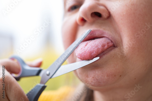 Close up of woman cutting tongue with scissors humorous concept silence censorship sarcasm stop talking idea metaphor facial expression, Metaphor for regretful speech gossip, saying too much