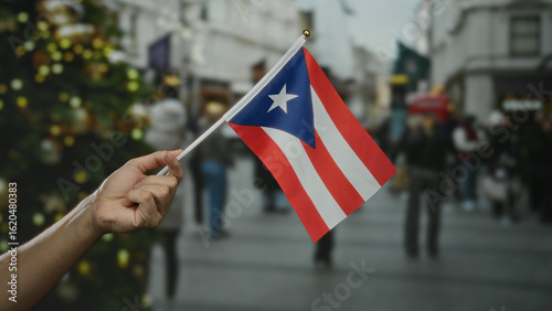 Obraz na płótnie Hand holding puerto rican flag outdoors in a crowded city street with blurred background