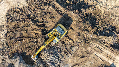 Aerial, overhead image of a excavator working on construction site moving dirt, earth.  Earthmoving, excavations, digging on soils	
