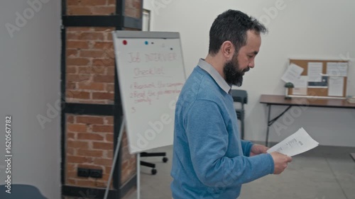 Medium panning shot of Caucasian male teacher giving resume samples to group of multiracial prison convicts serving criminal sentences in penitentiary institution, while conducting adaptation course