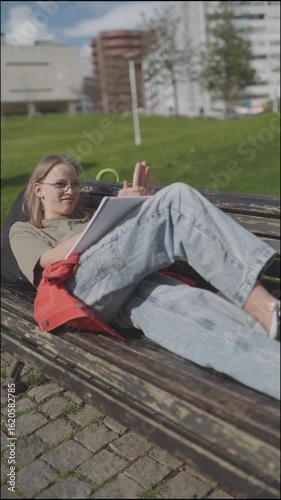 Young student relaxing and studying outdoors on a bench