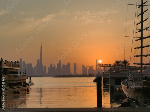 Fotografie Sunset skyline view of Dubai with silhouettes of boats on the water and the icon