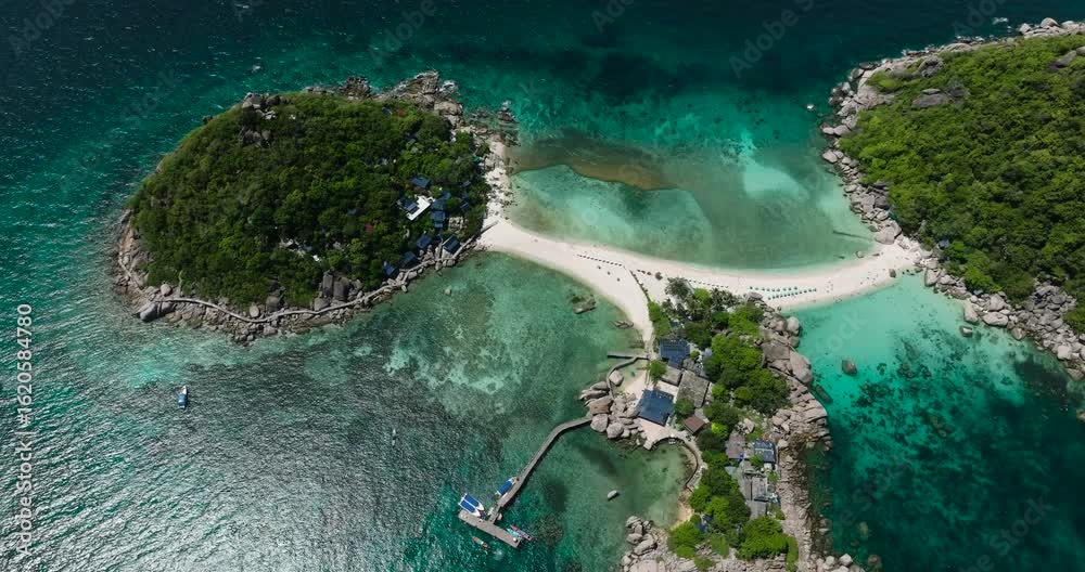 A tropical beach with turquoise water, white sand, and umbrellas under clear skies surrounded by natural beauty. Nang Yuan, Thailand.