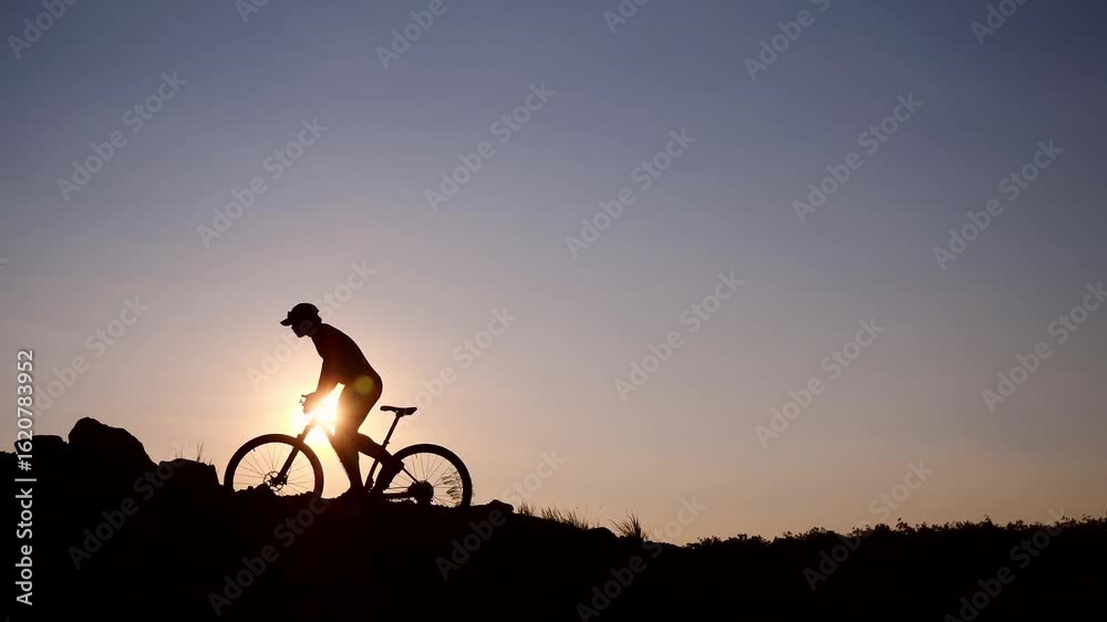 Silhouette Cyclist at Sunset: A lone cyclist navigates a rugged trail, their form silhouetted against the warm glow of the setting sun, embodying adventure and perseverance in the face of nature. Silhouette Cyclist at Sunset: A lone cyclist navigates a rugged trail, their form silhouetted against the warm glow of the setting sun, embodying adventure and perseverance in the face of nature.