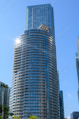 Photography Glass high-rise condo with curved balconies reflects sunlight in the South Core