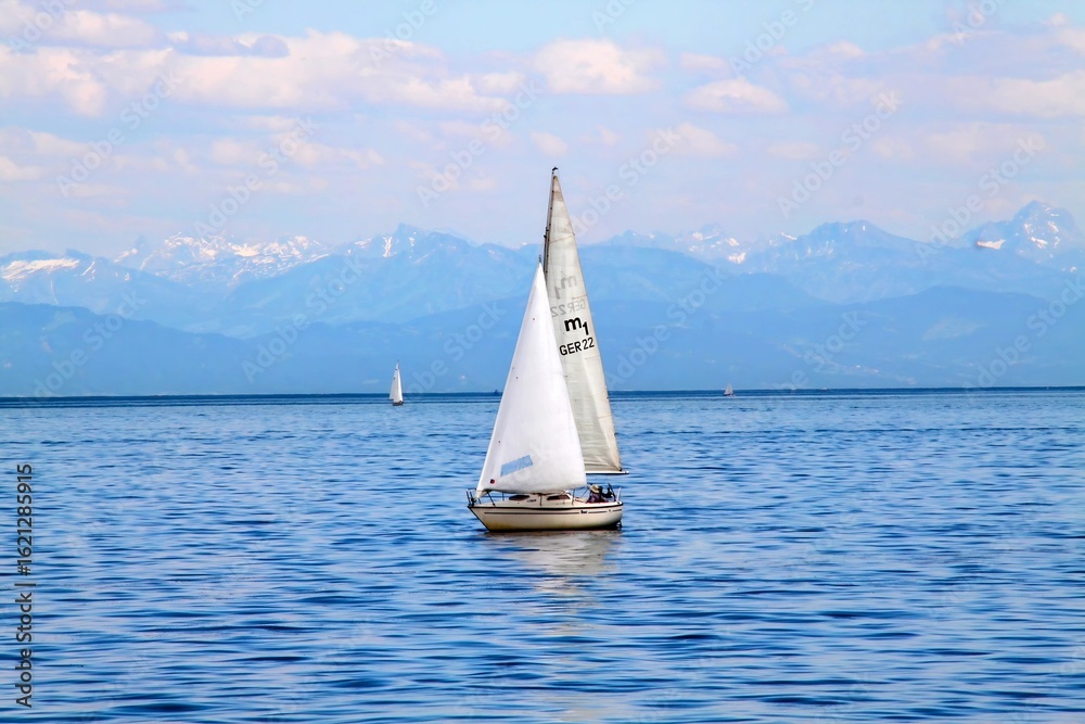 Naklejka premium Serene Sailboat on Calm Waters with Mountain Backdrop