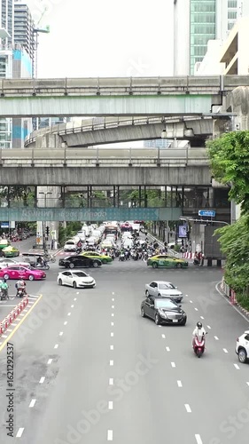 BANGKOK, THAILAND - AUGUST 2024 : View of street traffic at busy crossing. Many cars, motorbikes, tuk tuk and taxi on the road. Transportation concept video. Time lapse shot in daytime.