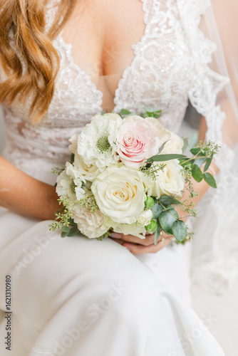 Bride in a lace wedding gown holding a wedding bouquet with white and pink roses