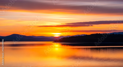serene sunset panorama: calm lake, silhouetted mountains, vibrant sky