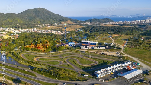Drone view of Beto Carrero World kart track and amusement park with coastal city in the background.