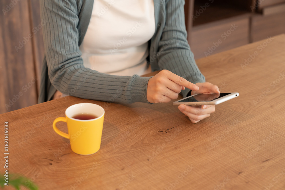 Obraz premium 部屋でスマホを見る若い女性 手元