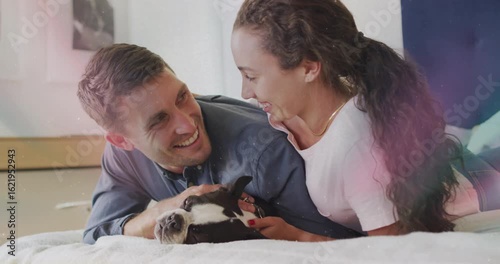 Couple leaning over dog on bed and starting loving petting while sharing laughter for mental health