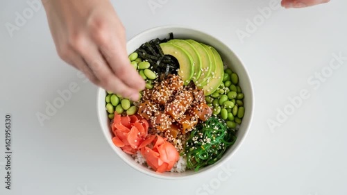Preparing a Poke Bowl: Adding Sesame Seeds to Fresh Tuna, Avocado, and Seaweed Salad