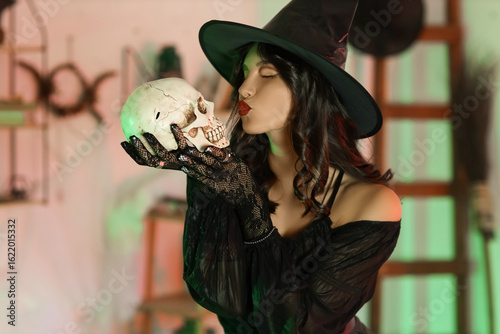 Young witch kissing skull a...