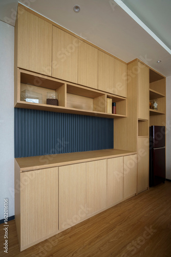 Custom built-in wooden cabinets and shelving in a modern office, featuring a dark blue fluted backsplash. Functional and stylish storage.