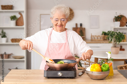Happy senior woman cooking ...
