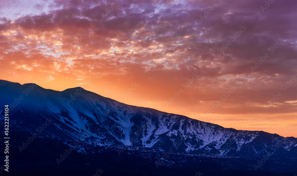 Fototapeta premium highland mountain landscape of beautiful sunset or sunrise behind nice mountain peaks and slopes in snow and majestic cloudy sky on background