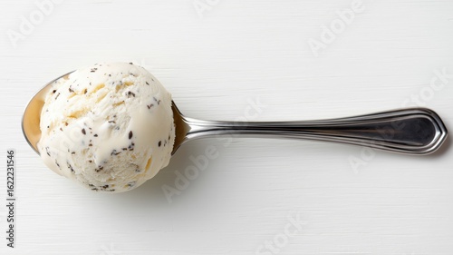Creamy ice cream sits on a silver spoon against a white surface, inviting a tasty treat.
