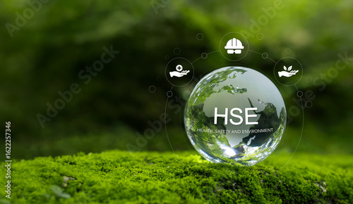Health, Safety and Environment HSE concept focusing on accident prevention, environmental protection, health and safety for business and organization. Crystal ball on moss in forest, green background.