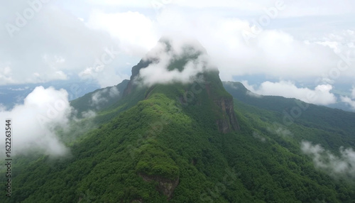 Brazil’s Pico da Neblina emerges above tropical rainforest as the country’s highest peak. Clouds part to reveal steep slopes covered in misty jungle.
